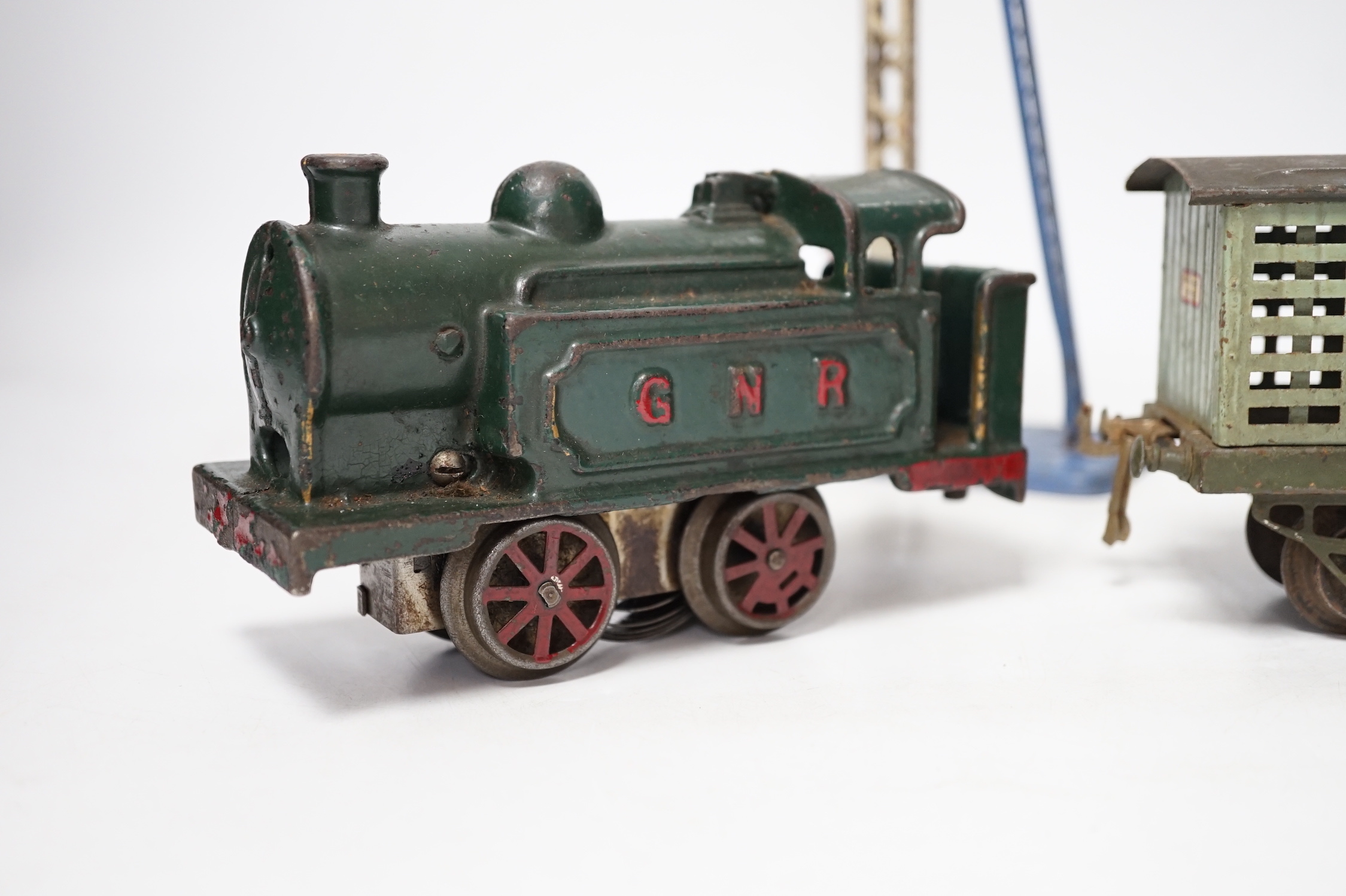 A collection of O gauge clockwork tinplate model railway, including a cast iron clockwork, GNR, 0-4-0T locomotive, six Hornby freight wagons, a small quantity of curved Bassett Lowke track sections and a few other items